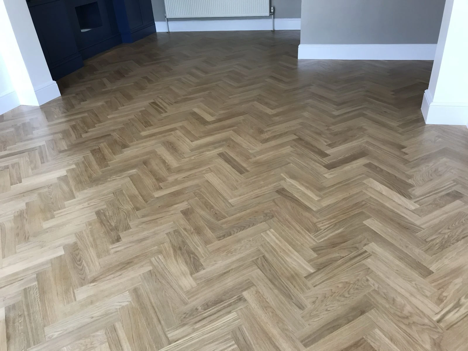 Herringbone oak parquet floor with navy alcove units in the background in Bristol