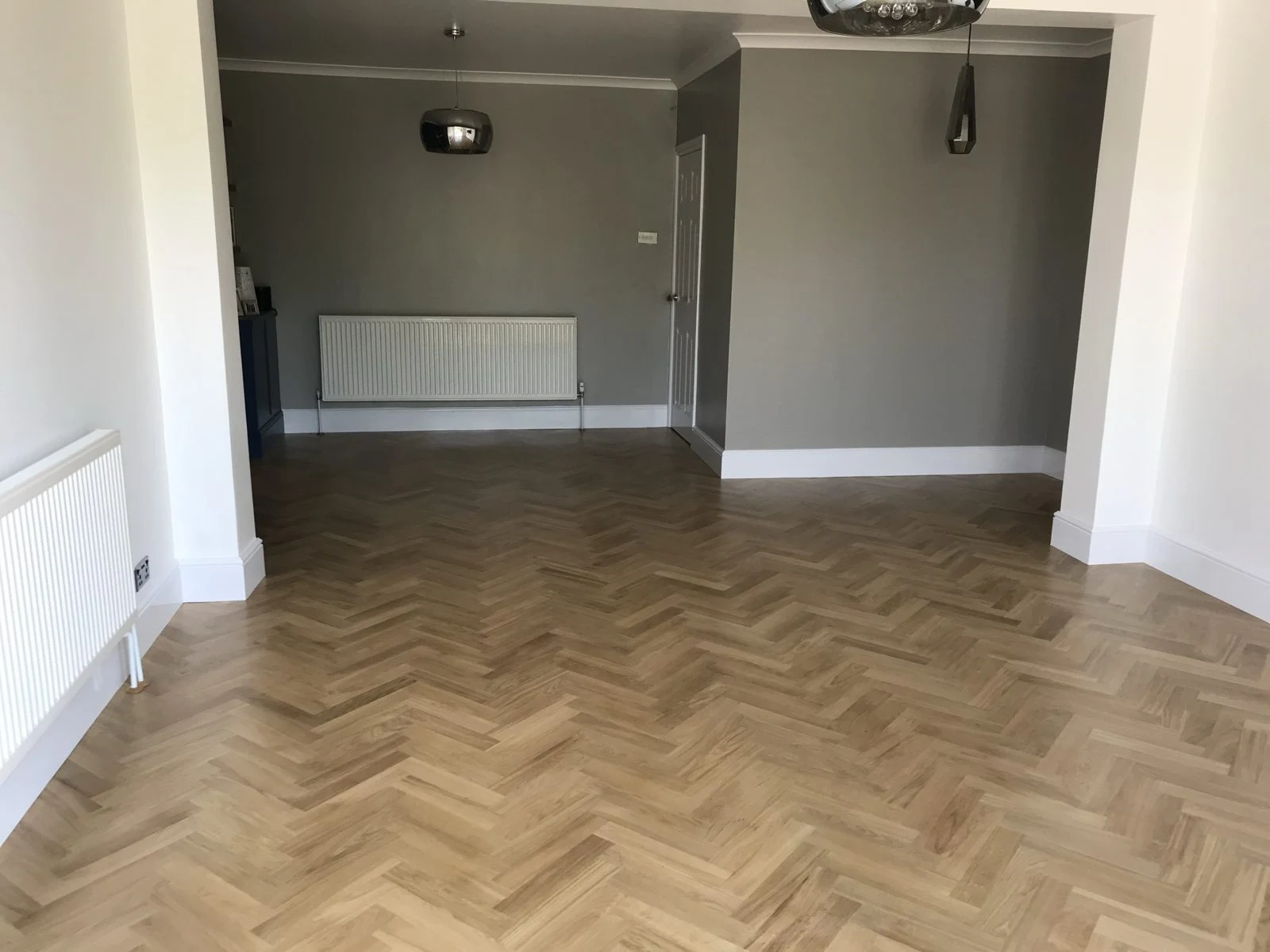 Herringbone oak parquet running through two connected living spaces in Bristol