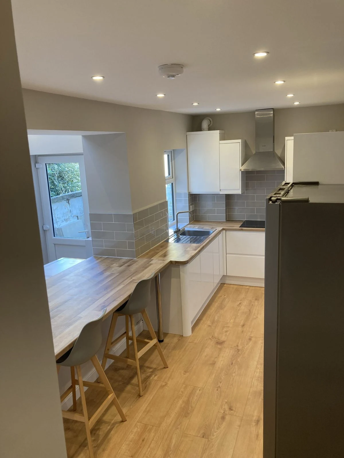 Galley view of a renovated kitchen with breakfast bar and bar stools