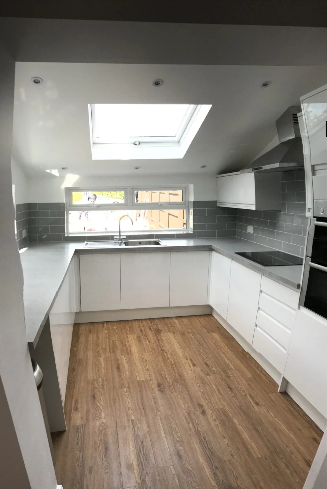 U-shaped white gloss kitchen with roof window and grey metro tiles