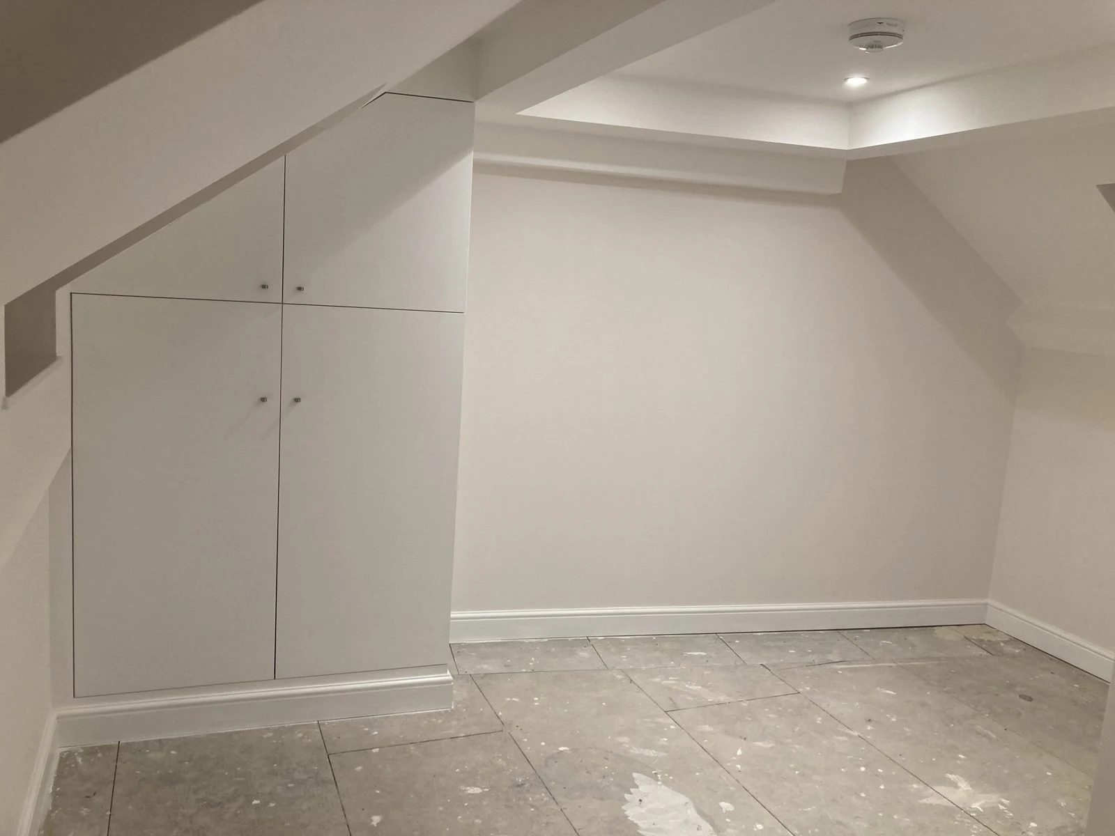 Fitted cupboards built under a sloped ceiling