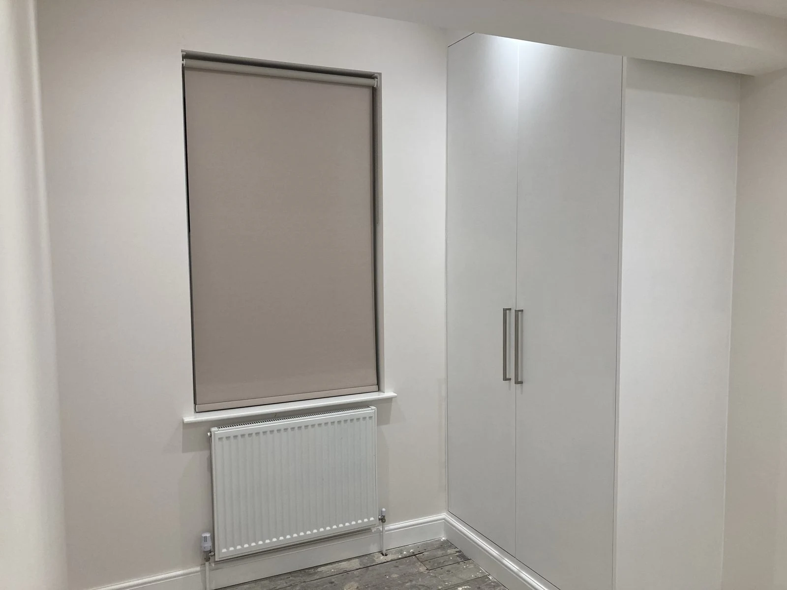 White fitted wardrobe beside a bedroom window