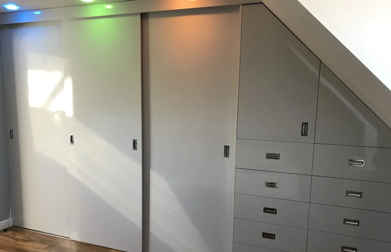 Fitted sliding wardrobes and drawers built under a sloped ceiling